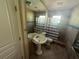 Bright bathroom with tiled walls and floor, a pedestal sink, modern lighting and a glass block shower at 7425 Riverbank Dr, New Port Richey, FL 34655