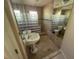 Modern bathroom featuring glass block shower, pedestal sink, tiled walls and flooring, and a large mirror at 7425 Riverbank Dr, New Port Richey, FL 34655