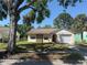 Charming single-Gathering home with a well-maintained lawn, featuring a beige exterior, an attached garage, and a stone column at 7425 Riverbank Dr, New Port Richey, FL 34655