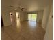 An empty living room with tile flooring, neutral paint, a ceiling fan and a large sliding door opening to the backyard at 7425 Riverbank Dr, New Port Richey, FL 34655