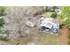 Aerial view of a home with an open carport and cars parked under it surrounded by trees at 8523 Hamster Dr, Zephyrhills, FL 33540