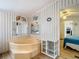 View of a bathroom with a corner tub, mirrors, striped wallpaper, and white shelves at 8523 Hamster Dr, Zephyrhills, FL 33540