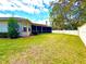 Spacious backyard featuring a screened-in lanai, lush green lawn, mature landscaping, and a privacy fence at 9006 Callaway Dr, Trinity, FL 34655