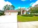 Charming single-story home featuring a three-car garage, landscaped lawn and red-trim accents at 9006 Callaway Dr, Trinity, FL 34655