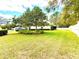 Expansive front yard with mature trees, landscaped garden beds, and a well-maintained lawn at 9006 Callaway Dr, Trinity, FL 34655