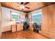 The wood-paneled office features built-in cabinets, a ceiling fan, and multiple workspaces, perfect for a home-based work environment at 9920 Alavista Dr, Gibsonton, FL 33534
