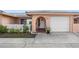 Charming home featuring a white garage door, arched entryway and well-maintained landscaping at 10467 Larchmont N Pl, Pinellas Park, FL 33782