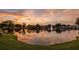 Tranquil pond view with a fountain reflecting the vibrant sunset and surrounding trees at 10467 Larchmont N Pl, Pinellas Park, FL 33782