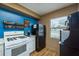This compact kitchen features a white range and a black refrigerator, set against a bold blue wall at 1273 Mission Cir, Clearwater, FL 33759
