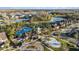 Aerial view showcases the community pool, a playground, and splashpad with pond and trees at 1555 Tallulah Ter, Wesley Chapel, FL 33543