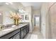 Bathroom with granite counters, dual sinks, decorative mirror, and tile flooring at 1598 Tallulah Ter, Wesley Chapel, FL 33543