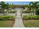 Inviting condo complex entrance with lush landscaping, palms, and stairway to the units at 1800 Mariner Dr # 9, Tarpon Springs, FL 34689