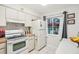 Functional kitchen featuring white appliances, ample cabinet space, and a view to the outside at 1800 Mariner Dr # 9, Tarpon Springs, FL 34689