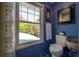 Cozy water closet has a white toilet, blue walls, tile floors, and a sunlit window with view to the outside at 3116 W Wallcraft, Tampa, FL 33611