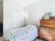 Bright bedroom featuring a quaint quilt, classic wooden dresser, and a view into the hallway, creating a cozy space at 35524 Quartz Lake Dr, Zephyrhills, FL 33541