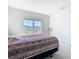 Bright bedroom featuring a large window overlooking the lawn and bed with patterned blanket at 35524 Quartz Lake Dr, Zephyrhills, FL 33541