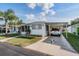 Charming single-story home with well-manicured lawn, carport, decorative compass rose on driveway, and mature landscaping at 37042 Lois Ave, Zephyrhills, FL 33542