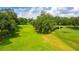 View of a golf course featuring mature trees, lush green grass, ponds, and a clear blue sky at 37042 Lois Ave, Zephyrhills, FL 33542