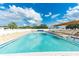 Outdoor community swimming pool surrounded by lounge chairs and shady awning featuring brick-patterned patio and safety equipment at 37042 Lois Ave, Zephyrhills, FL 33542