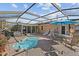 Relaxing screened-in pool area with lounge chairs, an umbrella table, and brick pavers at 6891 4Th S St, St Petersburg, FL 33713