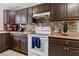 Close-up of kitchen featuring brown cabinets, white appliances, and tile backsplash at 7210 N Manhattan # 1822, Tampa, FL 33614