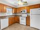 Functional kitchen featuring tiled floors, oak cabinets, white appliances, and plenty of natural light from the window at 8460 Calais N # 8406, Pinellas Park, FL 33781