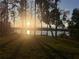 Backyard with mature trees and a lake view at sunset at 1301 Jen Ma Jo Ln, Lutz, FL 33549