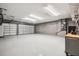 Well-lit three car garage featuring sealed flooring and bright lighting, providing ample space for parking and storage at 1301 Jen Ma Jo Ln, Lutz, FL 33549