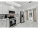 Modern kitchen featuring stainless steel appliances, white cabinets, stylish backsplash, and access to the outdoor pool area at 13635 Coronado Dr, Spring Hill, FL 34609