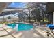 Screened-in pool with built-in hot tub, grill, and rock waterfall feature at 13635 Coronado Dr, Spring Hill, FL 34609