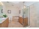 Well-lit main bathroom featuring double sinks, a soaking tub, a glass-enclosed shower, and travertine tile at 14 Somerset St # 5C, Clearwater, FL 33767