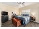 Bedroom with wood-look tile flooring, ceiling fan, television, and decorative furniture at 146 175Th Terrace E Dr, Redington Shores, FL 33708