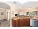 Kitchen with brown cabinets, granite countertops, stainless steel dishwasher, and adjacent living area at 146 175Th Terrace E Dr, Redington Shores, FL 33708
