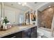 Well-lit bathroom featuring a granite countertop, dark wood cabinets, and a combined bathtub and shower at 15721 Starling Water Dr, Lithia, FL 33547