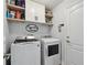 Bright laundry room featuring a washer and dryer, storage shelves, and door to the outside at 15721 Starling Water Dr, Lithia, FL 33547