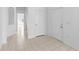 An empty foyer with white walls and white doors with beige tile flooring at 1847 Ravenridge St, Wesley Chapel, FL 33543