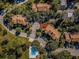 Aerial view showcasing the townhouses with green landscaping, mature trees, and a community pool at 2180 Clover Hill Rd, Palm Harbor, FL 34683
