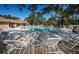 Relaxing pool area with lounge chairs and tables under a bright blue sky at 2180 Clover Hill Rd, Palm Harbor, FL 34683