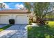 Charming exterior view of home featuring an attached two-car garage and mature landscaping at 3066 Pelican Pl, Clearwater, FL 33762