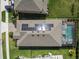 Aerial view of a home with solar panels, screened-in pool, manicured lawn, and neighboring houses at 4016 Cadence Loop, Land O Lakes, FL 34638