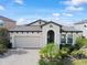 Beautiful single-story home showcasing an arched entryway, lush landscaping, and a convenient two-car garage at 4016 Cadence Loop, Land O Lakes, FL 34638
