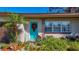 Close-up of a welcoming entrance featuring a bright teal door, decorative wreath, and vibrant garden at 4100 Narvarez S Way, St Petersburg, FL 33712