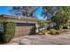 Attractive single-story home with a brown garage door, mature trees, and a beautifully landscaped front yard at 4100 Narvarez S Way, St Petersburg, FL 33712