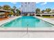 Relaxing pool with clear water surrounded by palm trees and a covered lounge area for residents to enjoy at 4939 Floramar Ter # 208, New Port Richey, FL 34652