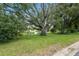 Backyard featuring a large tree, green grass, and a view of the pond at 6141 Chesham Dr # 7, New Port Richey, FL 34653