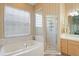 Bright bathroom showcases a tub, glass-enclosed shower, and wood cabinets with ample counter space at 10105 Holly Berry Dr, Weeki Wachee, FL 34613