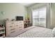 Sunlit bedroom with dresser, TV, and a large window with natural lighting at 10105 Holly Berry Dr, Weeki Wachee, FL 34613