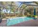 The screened pool features a blue tile border, with an umbrella, and ample surrounding deck space for relaxation and recreation at 10105 Holly Berry Dr, Weeki Wachee, FL 34613