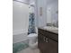 Powder room features a dark wood vanity with granite top, toilet and tub shower with blue accents at 13359 Golden Lime Ave, Spring Hill, FL 34609
