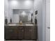 Bathroom features a double vanity with dark wood cabinets, granite counters, and a large mirror at 13359 Golden Lime Ave, Spring Hill, FL 34609